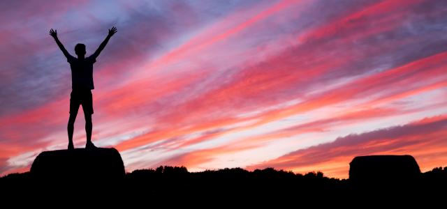 silhouette of man standing on high ground under red and blue skies by Benjamin Davies courtesy of Unsplash.